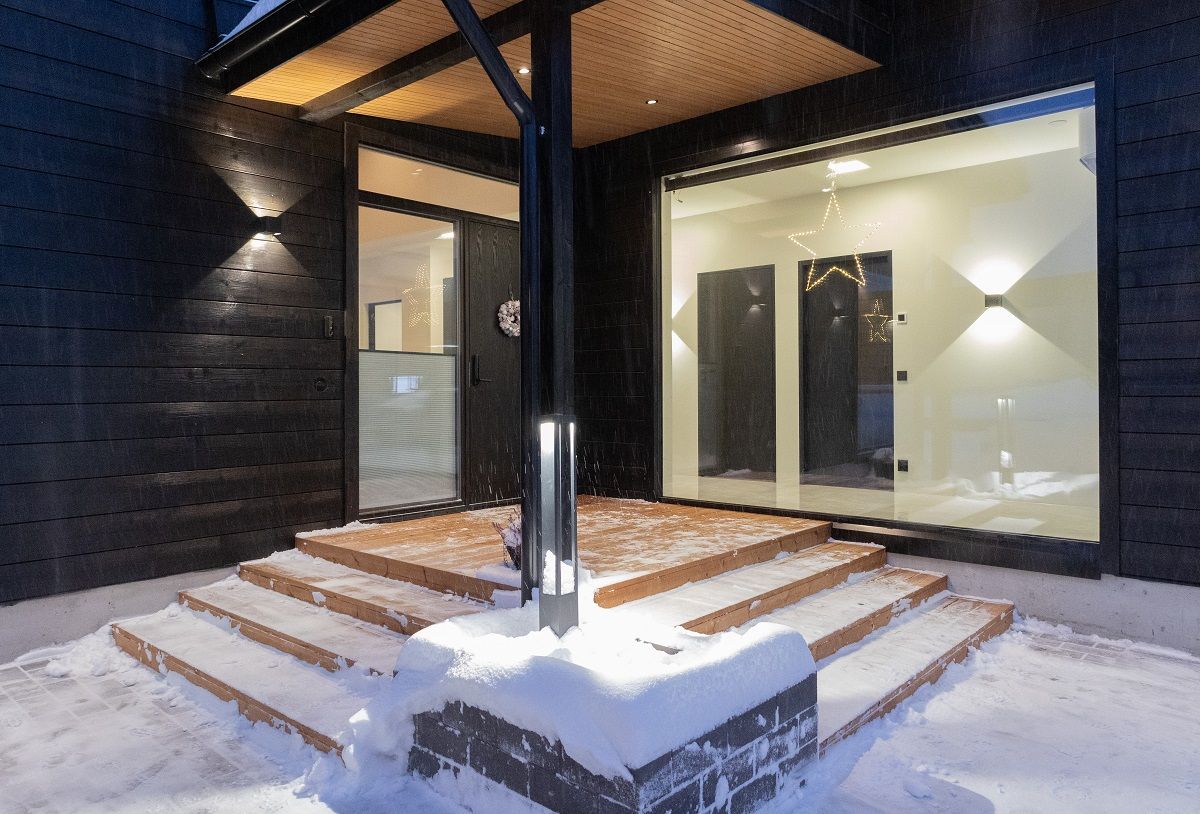 L'ingresso della casa è splendidamente illuminato. Oltre alle luci nere delle pareti esterne e al pilastro luminoso nero della vasca di coltivazione, l'ingresso è illuminato da faretti neri da 9W sul soffitto